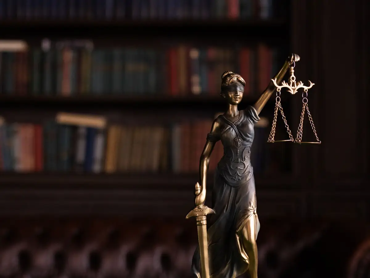 Kitaplık önünde adalet heykelciği ve tokmak